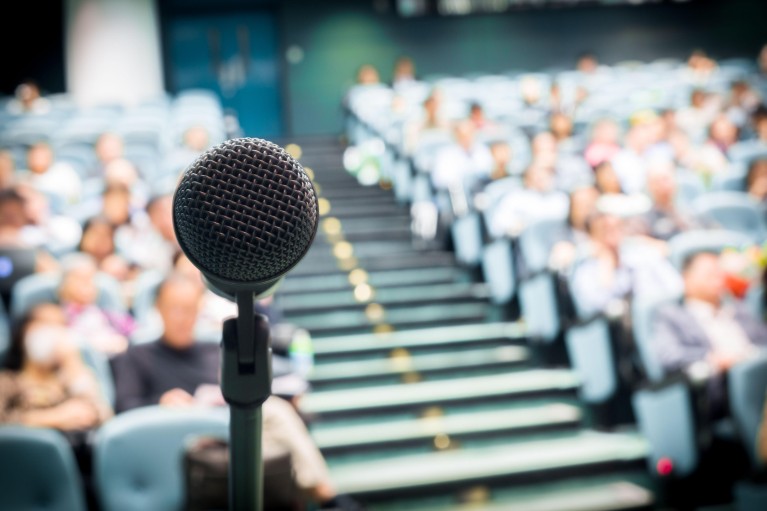 View of a microphone in front of an auditorium of seated people
