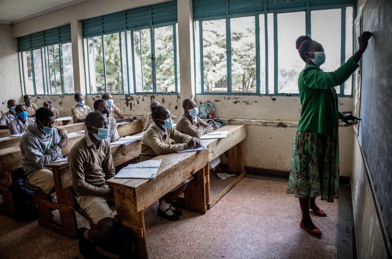 A teacher teaches a class while they all wear face masks