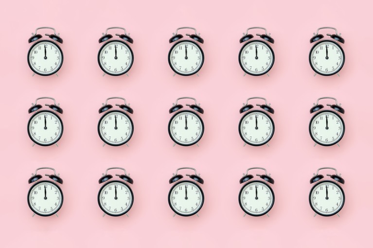 A repeated pattern of black alarm clocks on a pale pink background