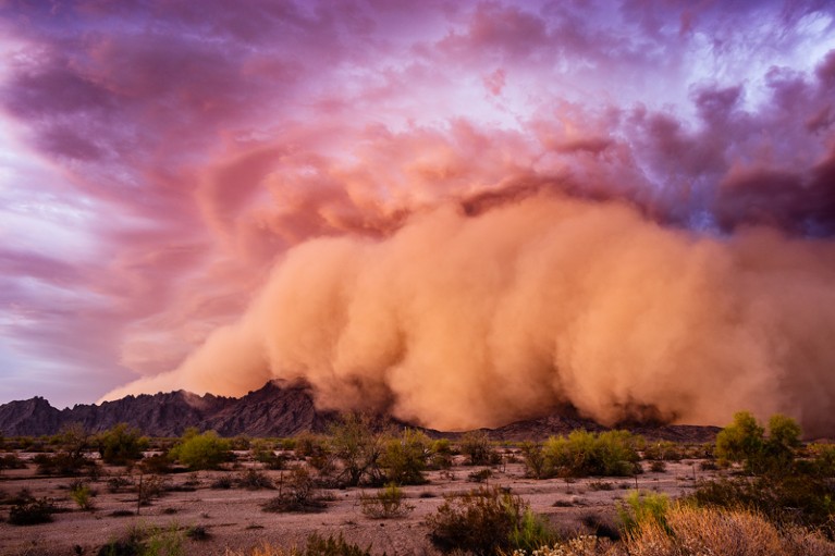Dust storm clouds moving over hills in the Arizona desert at sunset