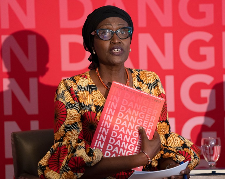 温妮·拜安伊玛(Winnie Byanyima)手里拿着一本红色小册子，封面上重复着“处于危险之中”的字样