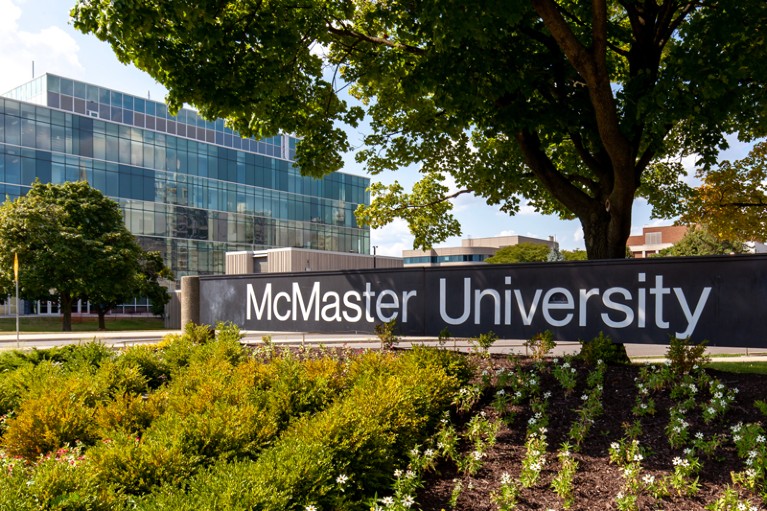 The McMaster University sign is seen with a glass building in the background on campus