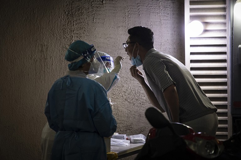 Health workers perform a Covid-19 swab test on a resident in the Xuhui district of Shanghai, China
