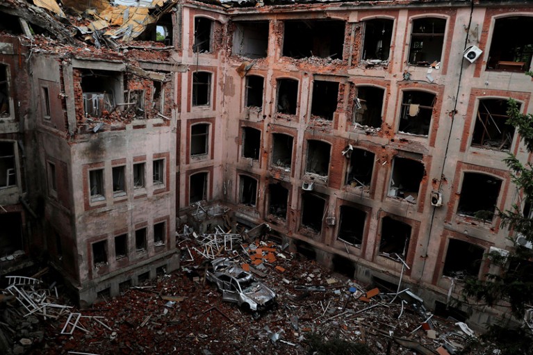 A general view of a destroyed building of Kharkiv National University with a car parked at the bottom