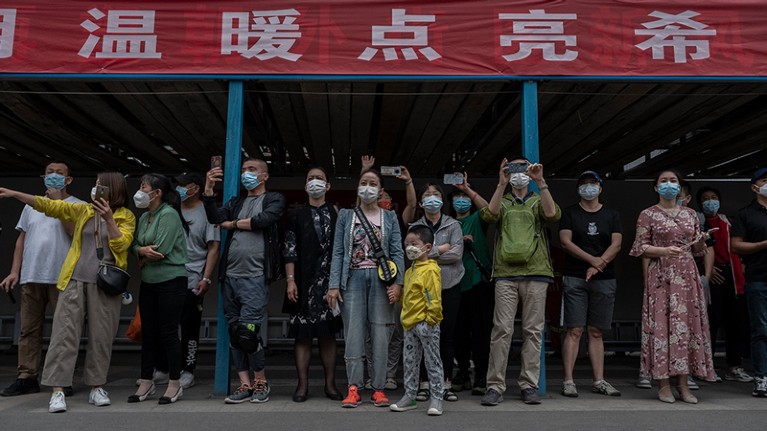 中国北京一所高中外，家长和亲戚戴着防护口罩。