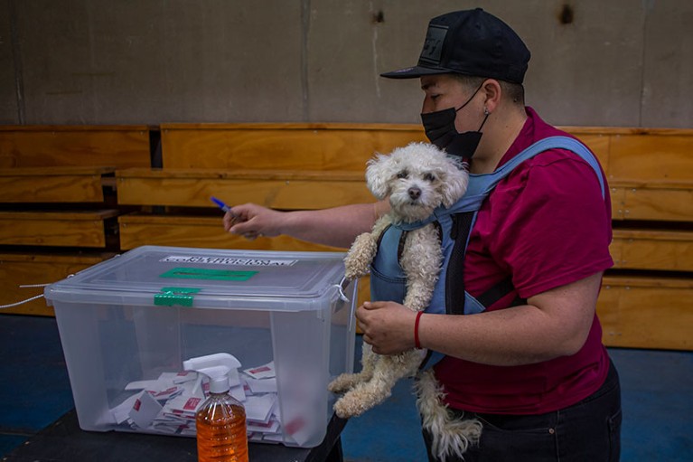 A person attends to vote with his puppy in Maipú, Santiago de Chile.