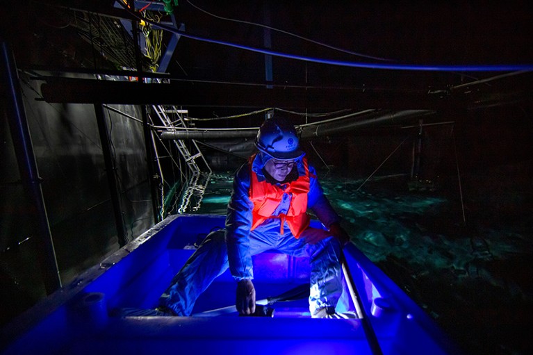 Astrophysicist Cao Zhen sits in a boat across in a water-filled cavern at the Large High-Altitude Air Shower Observatory