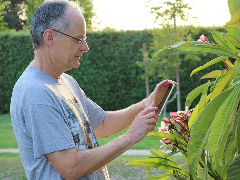 Patrick Gavit taking picture of insect on plant to post on iNaturalist.