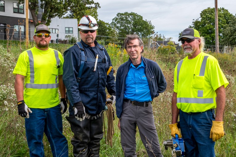 Three wastewater engineers wearing protective hi-vis clothing pose with Dr. Martin Shafer