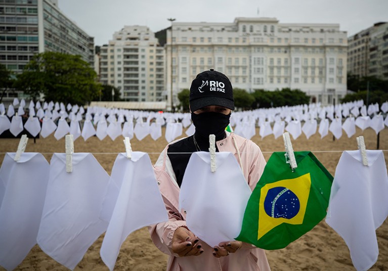 A person places white handkerchiefs symbolizing farewell in homage to 600,000 victims of the coronavirus pandemic in Brazil.