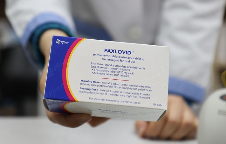 A pharmacist holds a pack of Paxlovid