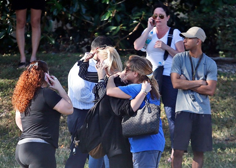Anxious family members wait for news of students as two people embrace, in Parkland, Florida, after a mass shooting.