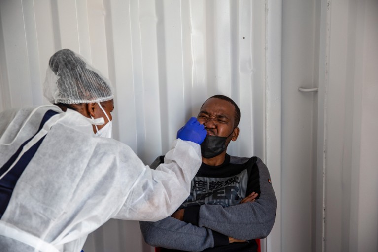 A man screws up his face as a health worker inserts a swab into his nose to test for COVID-19