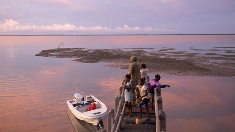 People stand on a jetty on Boigu Island, Australia.