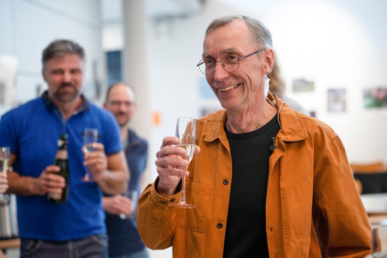 Svante Pääbo holds a glass of champagne while he celebrates his Nobel Prize win with colleagues