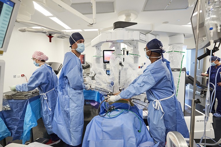 Two people perform surgery on a patient using a robotic surgical system