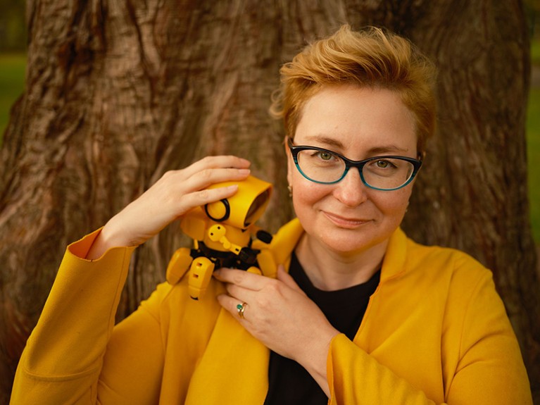 Portrait photo of Ganna Pogrebna holding a robot on her shoulder