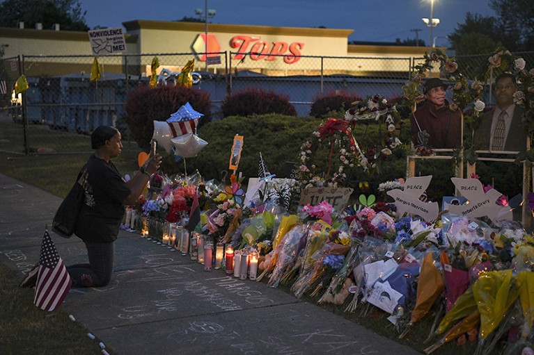 A woman kneels at a memorial to mass shooting victims outside the Tops Friendly Market in Buffalo, on May 25, 2022.