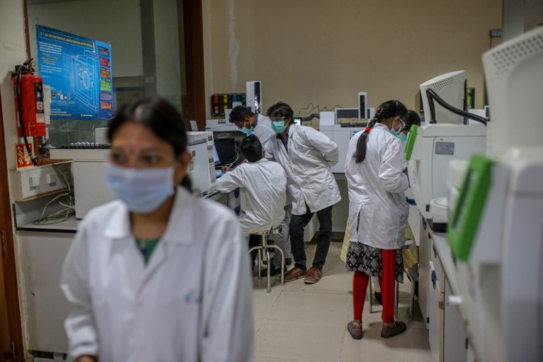 Employees in white lab coats and masks work in a research laboratory in India