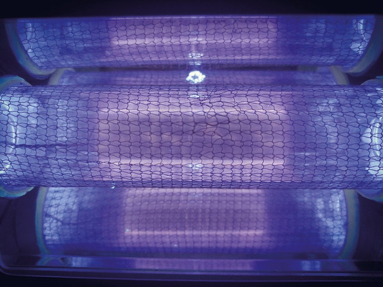 Close-up of krypton chloride excimer lamp emitting purple light. The lamp consists of three cylindrical sections.