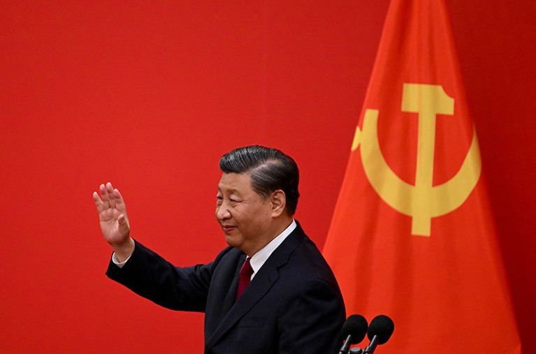 China's President Xi Jinping waves next to China's flag after introducing the members of the new Politburo Standing Committee.