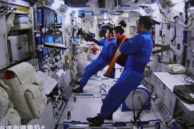 Three Shenzhou-13 astronauts watch a screen on the Tiangong space station