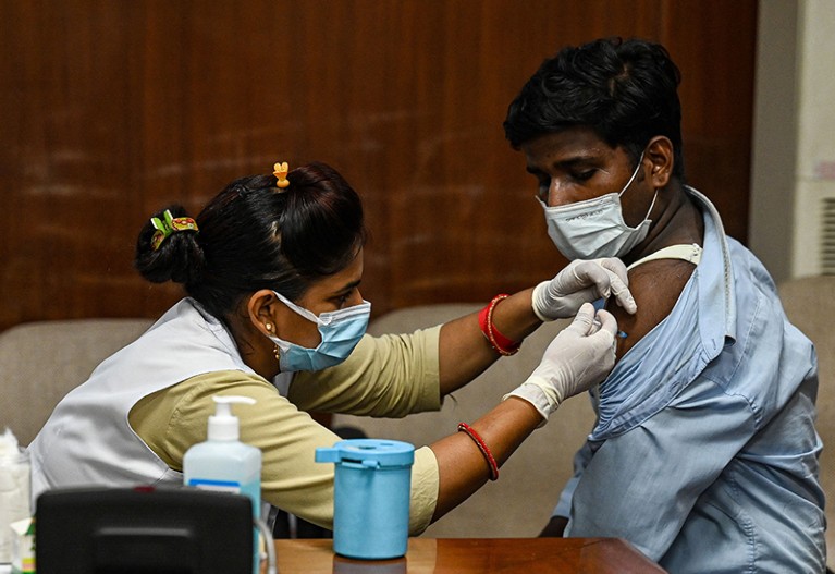 Woman in a mask inoculate man in a mask.