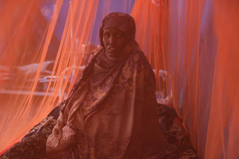 A woman sits inside a mosquito net at the Gode Referral Hospital, in the town of Gode, Somali Region, Ethiopia.
