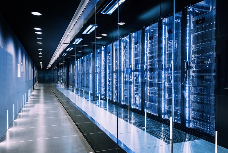 Data center in server room with server racks behind glass cases.