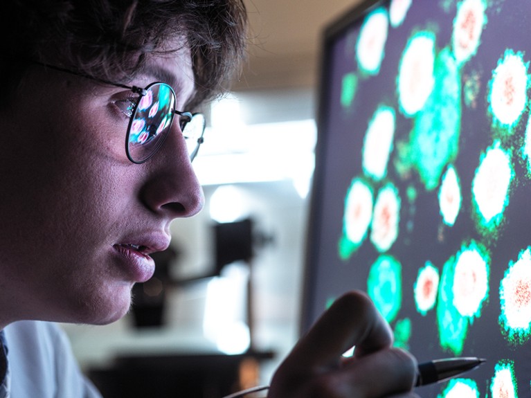 Male scientist researching on biological cell on computer screen in laboratory.