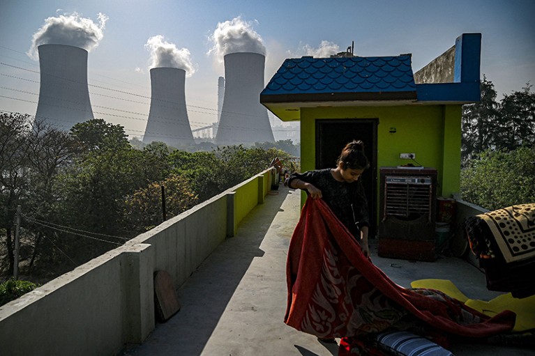 A girl folds a blanket at her house rooftop near the coal-fired Thermal Power Corporation (NTPC) plant in Dadri, India.