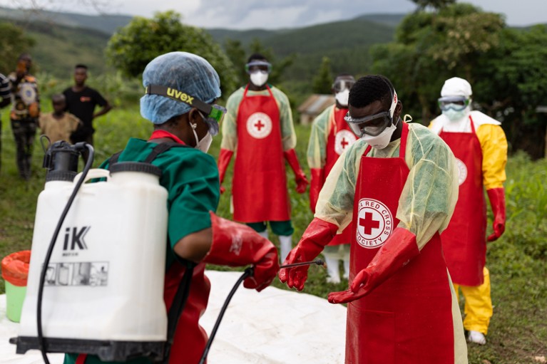 Ugandan Red Cross workers wearing PPE sanitize their gloves.