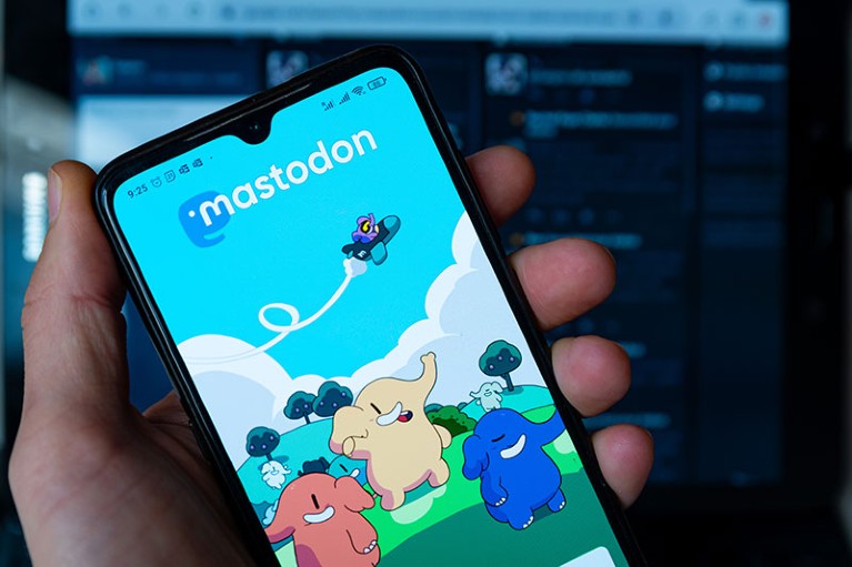 The Mastodon homepage is seen displayed on a mobile phone screen held in a hand.
