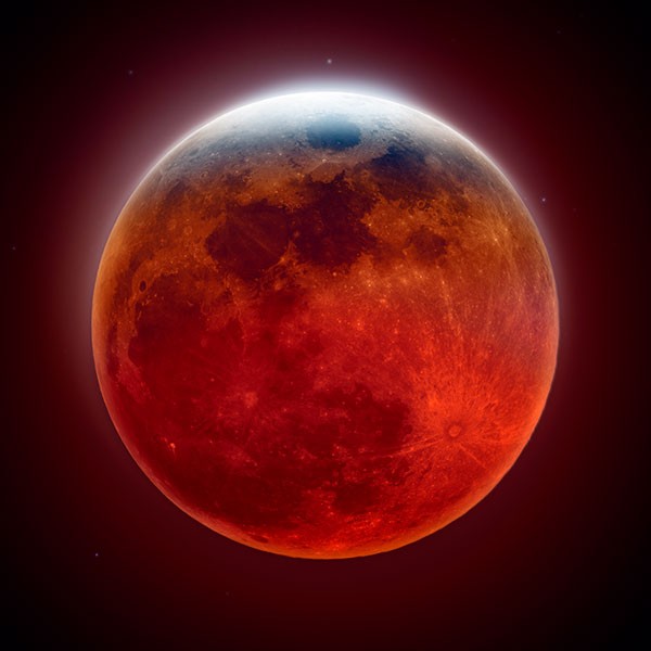 The lunar surface tinted red by the Earth’s shadow during the total lunar eclipse.