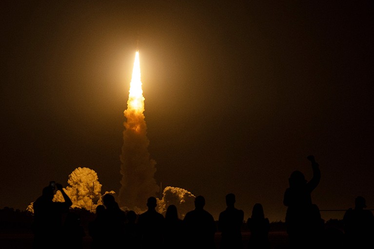 Spectators cheer as the Artemis I unmanned lunar rocket lifts off at NASA's Kennedy Space Center in Cape Canaveral, Florida.