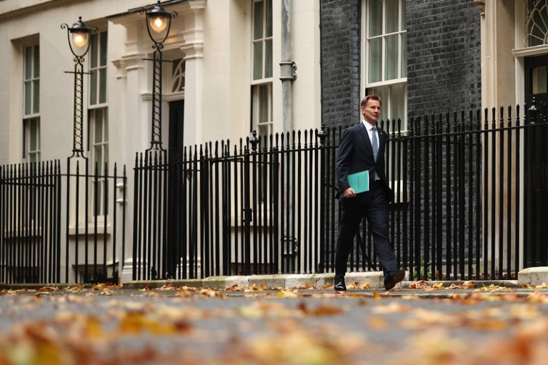 Low-angle view of Jeremy Hunt leaving Downing Street holding the Autumn Statement