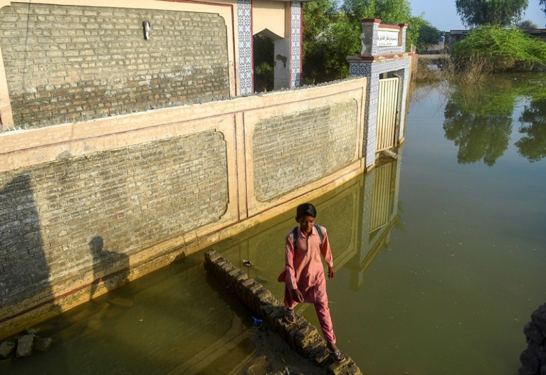 A flood-affected student walks past a deluged government primary school in Chandan Mori, in Dadu district, Pakistan.