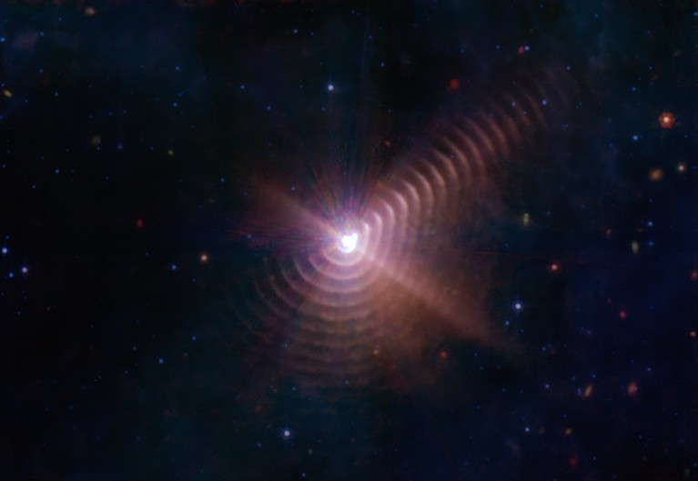 Shells of cosmic dust created by the interaction of binary stars appear like tree rings that spiral from around Wolf-Rayet 140.