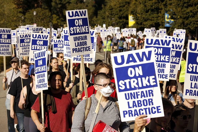 Academic workers and their peers in the University of California system hold signs and strike for better wages and conditions.
