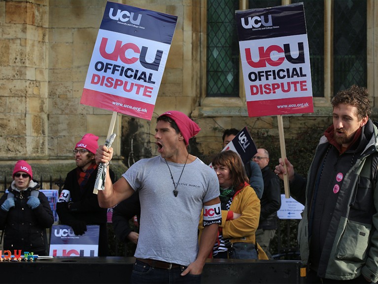 Members of a picket line outside a stone building hold signs reading 'UCU official dispute'.