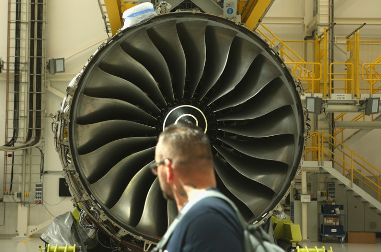 A Rolls-Royce employee walks past a Rolls-Royce Trent XWB airplane engine