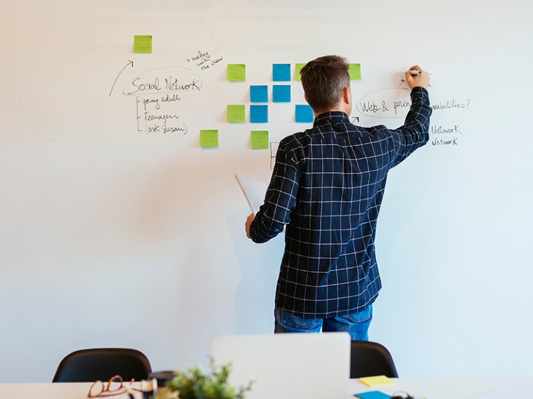 Businessman in office writing on whiteboard.