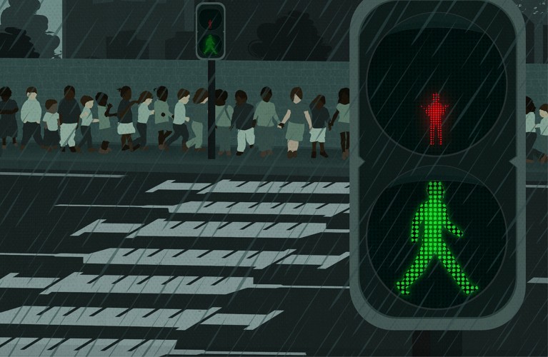 A pedestrian crossing with green lights for adults and red lights for children. Many children are held back at the crossing.
