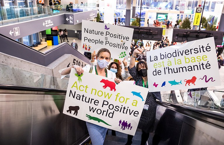 Delegates holding biodiversity placards ride an escalator at COP15 conference in Montreal 7th December 2022