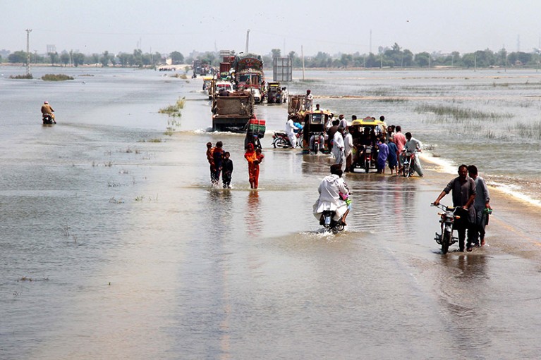People cross a flooded highway in Dadu district, Sindh province, Pakistan, 30 August 2022