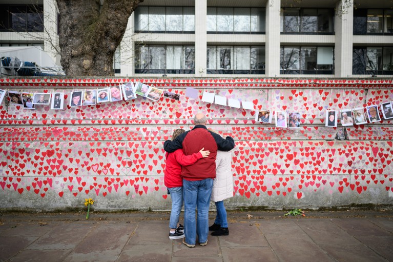 Members of the public embrace as they view the Covid Memorial Wall in London