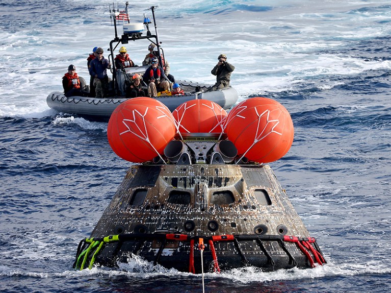NASA's Orion Capsule is drawn into the well deck of the USS Portland during recovery operations after it splashed down.