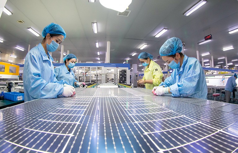 Workers wearing PPE make solar photovoltaic modules for export at a factory in Nantong, east China's Jiangsu Province.