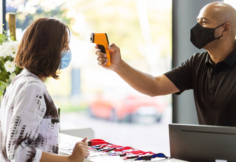 Front desk worker checking temperature of a conference attendee.