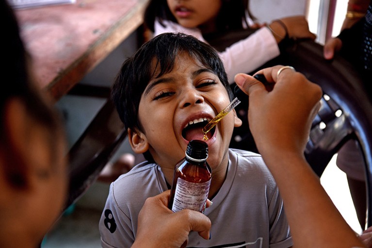 A child receiving a dose of medicine from a bottle.